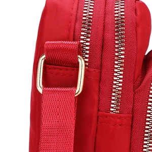 Red nylon crossbody phone bag with double zipper and golden metal buckle details