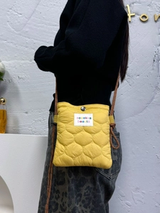 Detail of yellow quilted crossbody bag with adjustable rope strap and brand patch