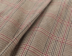 Close-up of houndstooth plaid fabric showing brown and beige wool blend texture