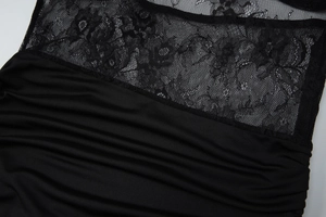 Détail rapproché de la dentelle florale noire et du tissu plissé drapé de la robe