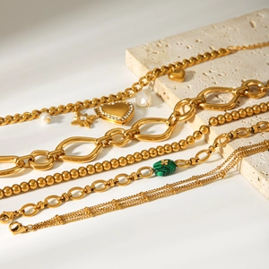 Detailed view of 18k gold plated chains with malachite stone and heart charms on stone