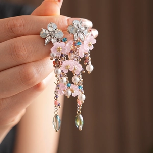 Dettaglio di orecchini vintage a fiore con petali rosa, perle e nappe a goccia