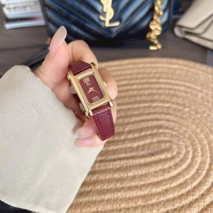Close-up of a vintage gold ladies watch with red leather strap and rectangular dial