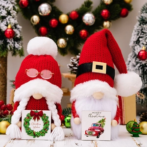 Close-up of festive Christmas gnomes with knitted hats holding wooden holiday message signs