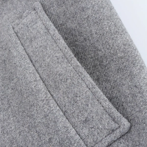 Detail of pocket stitching on a long grey wool coat with visible fabric texture