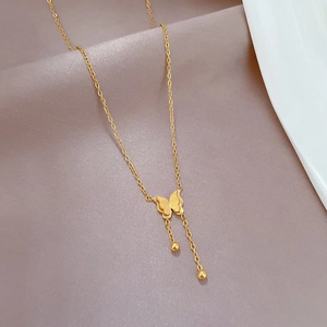 Detail of gold butterfly tassel pendant necklace on a soft silk background