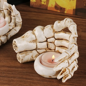 Gothic skull hand resin candle holder with pink tealight on dark wood table
