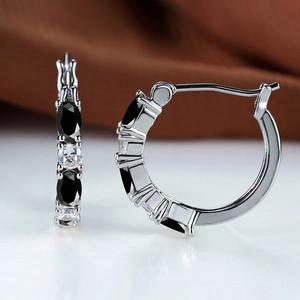 Close-up of silver hoop earrings with alternating black and white zircon stones