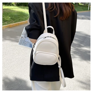 Outdoor street style shot of a woman wearing a cream white mini PU leather backpack