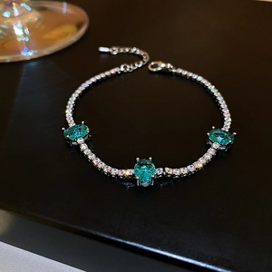 Macro detail of silver bracelet with three Paraiba blue gems on a sleek black background