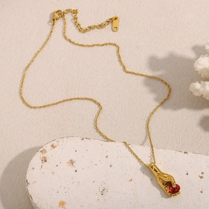 Détail d'un pendentif main en or 18 carats tenant une pierre de cœur rouge sur pierre