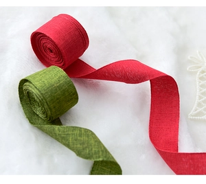 Close-up of red and green linen Christmas ribbons on soft white faux fur background