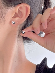 Detail of 925 silver heart stud earrings with black enamel and a small bow design