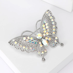 Macro detail of a silver butterfly brooch with iridescent stones on a white stand
