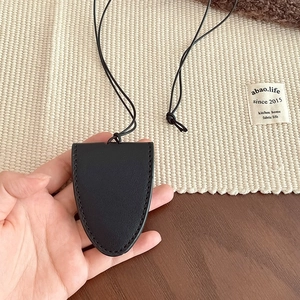Detail shot of a black leather key holder necklace pendant with a hanging strap