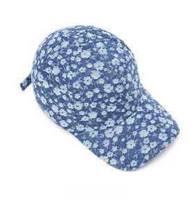 Top view of blue denim baseball cap with white floral pattern and distressed details