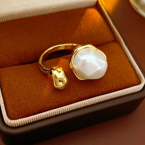Détail d'une bague dorée avec perle ovale dans un écrin de luxe en velours marron