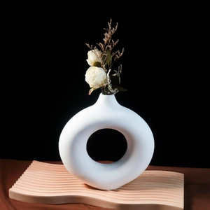 Vaso a ciambella in ceramica bianca con rose essiccate su vassoio in legno testurizzato