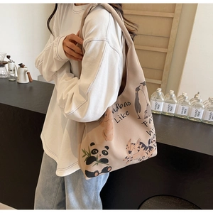 Detail of canvas tote bag with panda and tiger prints shown in a cozy cafe setting