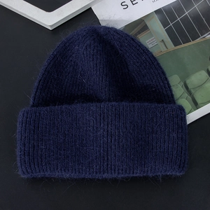 Detailed close-up of dark blue knit winter hat with premium long plush texture and softness