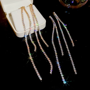 Detail view of long tassel earrings with sparkling white crystals on gold base