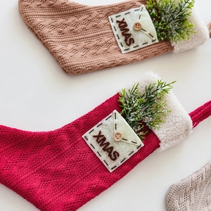 Knitted Christmas stockings with white faux fur trim and XMAS felt patch on white background
