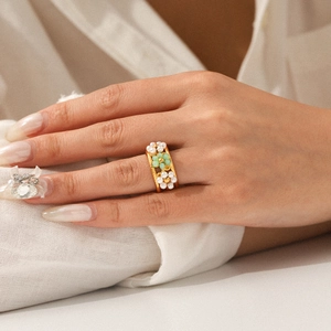 Detail of bohemian gold ring featuring white pearls and green beads in floral design
