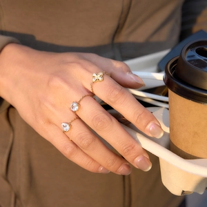 Detailed view of adjustable gold chain rings with pear and round zircon on a model's hand