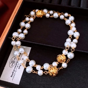 Double-layered pearl necklace with golden hollow carved metal beads in a jewelry box