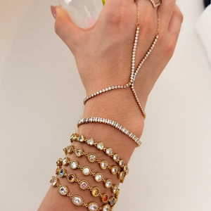 Detail of layered gold bracelets and ring set featuring sparkling crystals and zircons