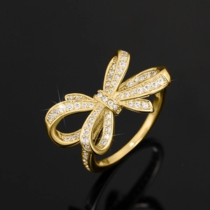 Détail macro d'une bague nœud dorée luxueuse avec pavé de zircons brillants sur fond noir