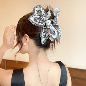 Macro view of black and white paisley bow hair clip on a model's elegant bun hairstyle