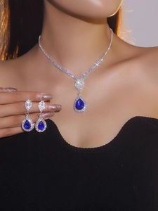 Close-up of bridal jewelry set with pear-cut blue crystal necklace and earrings
