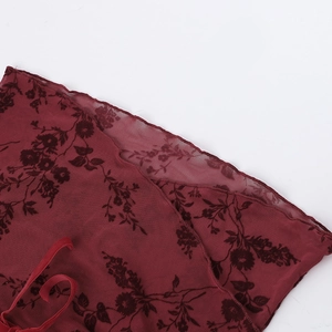 Gros plan sur tissu en tulle bordeaux avec flocage floral velours et détail ruban