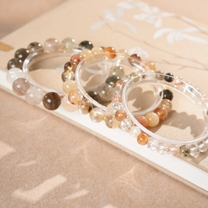 Gros plan détaillé de bracelets en cristal de quartz empilés sur un livre floral vintage