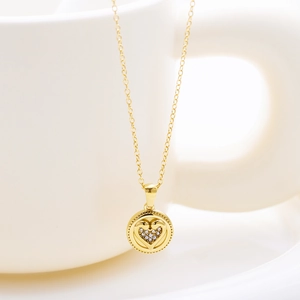 Close-up of golden necklace with a zircon-encrusted heart within a round pendant