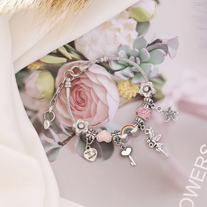 Macro detail of silver charm bracelet with pink crystals and rainbow heart pendants