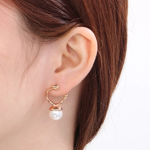 Close-up of model wearing geometric rose gold earrings with round white pearl drops