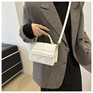Detail of white quilted crossbody bag with golden hardware and long shoulder strap