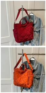Quilted tote bags in dark red and orange with cross-stitch patterns and adjustable straps
