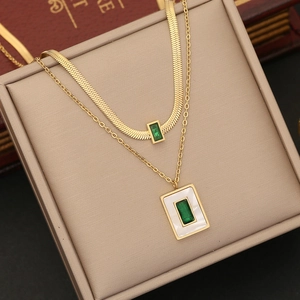 Close-up of a double-layered gold stainless steel necklace with green emerald pendants