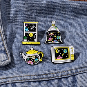 Set of 4 creative galaxy enamel pins featuring space motifs on denim fabric jacket