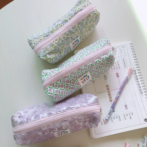 Estuches de lona con flores y encaje con cremalleras rosas sobre un escritorio