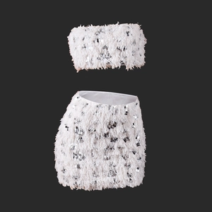 Detailed view of white two-piece set with sequins and feather textures on dark background