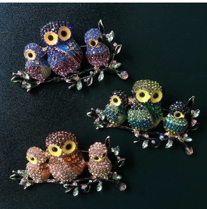 Detailed close-up of three colorful rhinestone owl brooches on a dark textured background