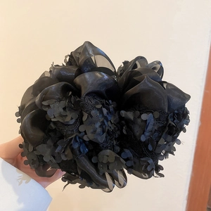 Détail d'une pince à cheveux fleur en organza noir avec des sequins et textures multicouches