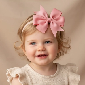 Detail of pink ribbed ribbon bow on a soft nude-colored stretchy nylon baby headband