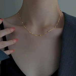 Close-up of minimalist gold beaded snake chain choker worn on a model's neck