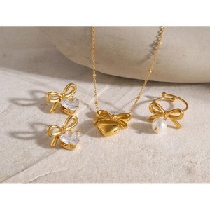 Golden bow jewelry set featuring a heart necklace, stud earrings, and a pearl ring