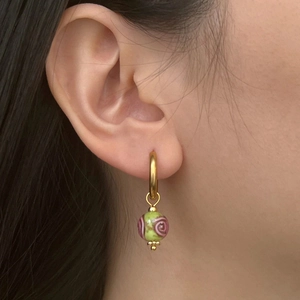 Detail of Chinese style heart porcelain earring with green and pink enamel on a gold hoop